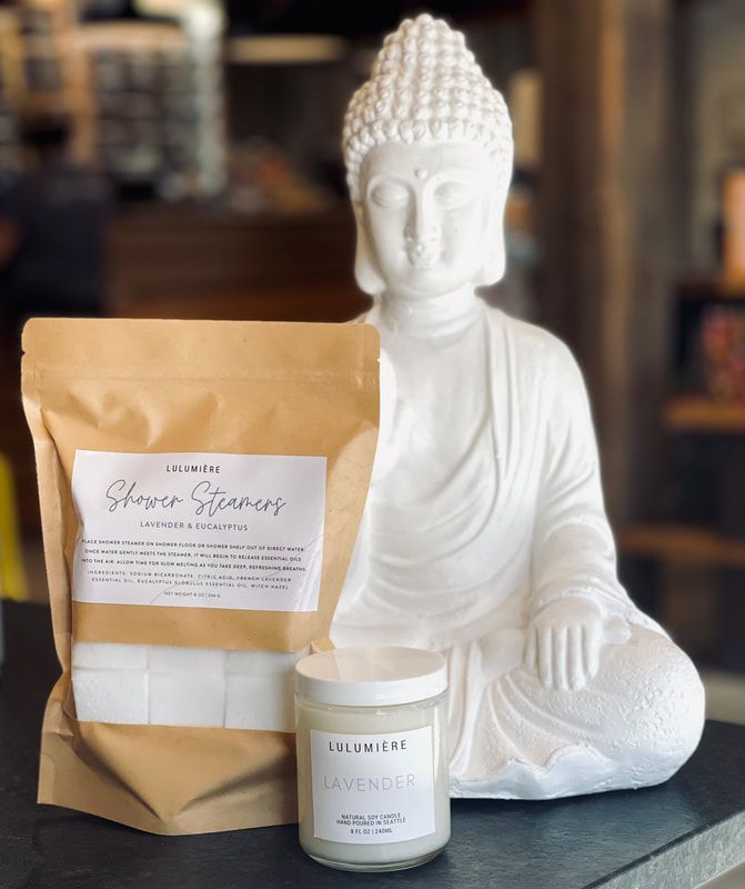 White Buddha statue beside a tan pouch and white candle on a tabletop