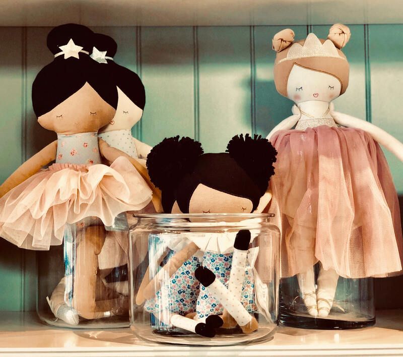 Three handmade dolls in jars with peach and cream dresses on a shelf