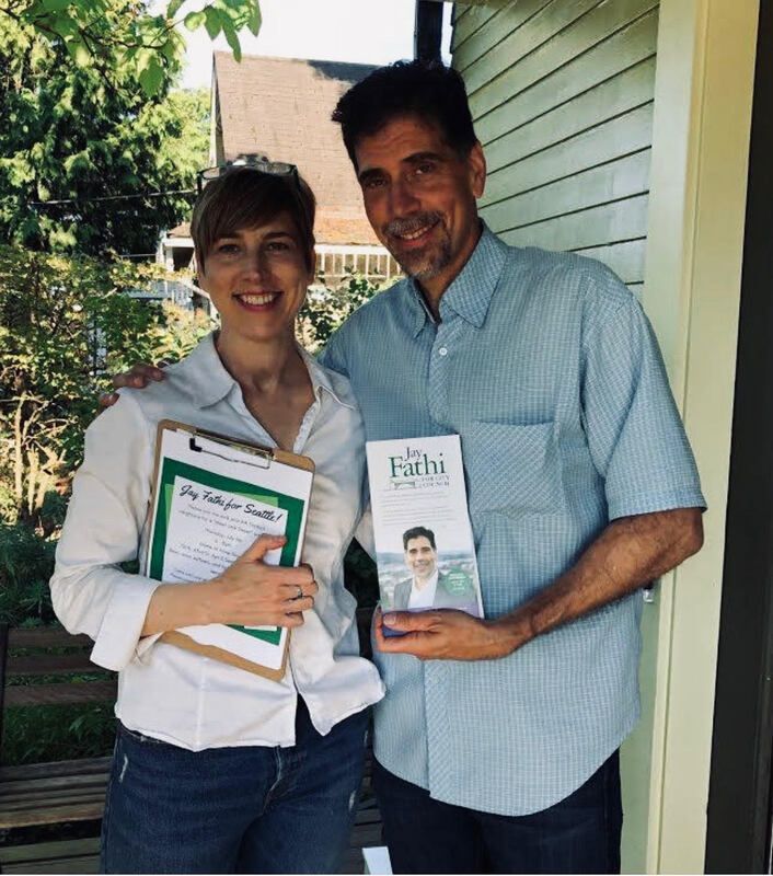 Two people smiling on a porch, each holding a book in a home exterior setting.