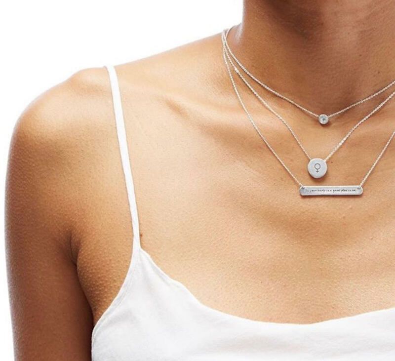 Woman wearing layered silver necklaces over a white camisole