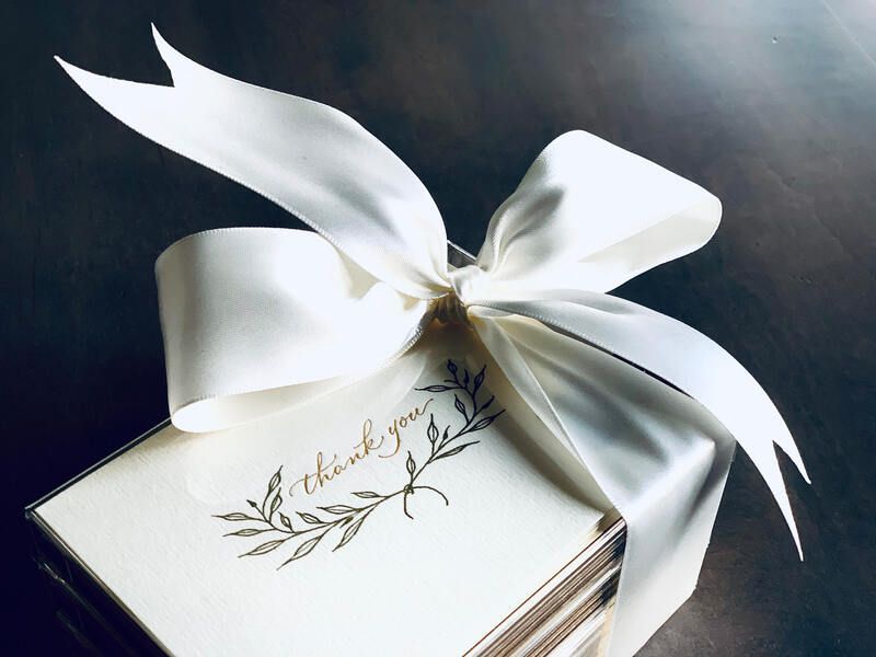 White gift box with a silver ribbon bow and a delicate floral design on top