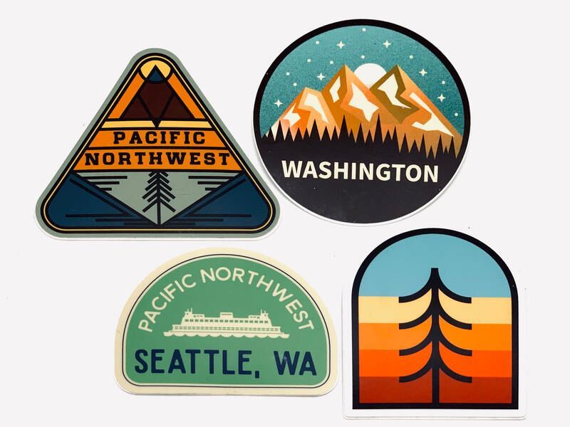 Four Pacific Northwest stickers: Washington mountains, Seattle WA, and a sunset tree design.