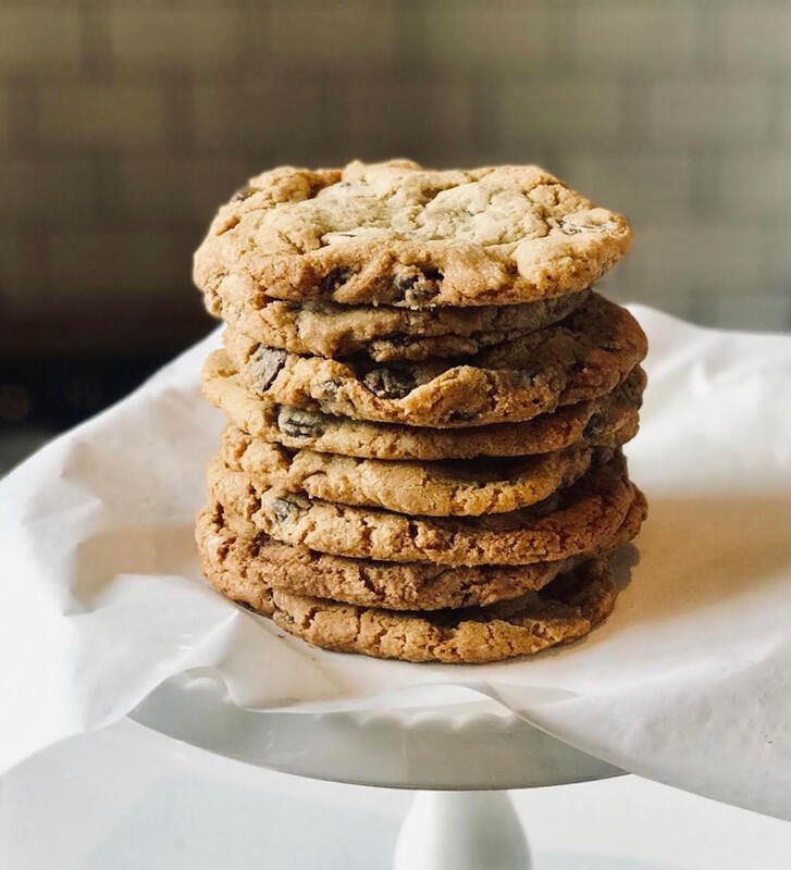 Stack of homemade chocolate chip cookies on a white plate with parchment paper