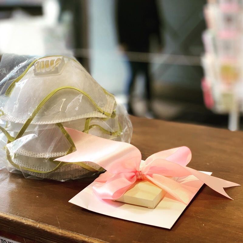 Gift-wrapped item with pink ribbon and gold accents on a wooden table
