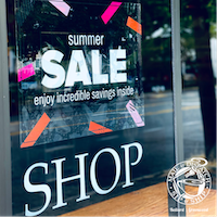 Storefront window with “summer SALE” sign and large “SHOP” lettering