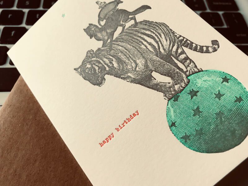 Greeting card with a tiger and a green starry ball on a textured beige background