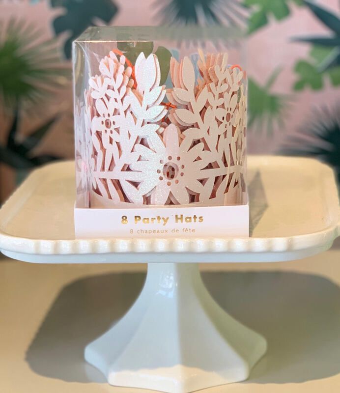 White cake stand with a floral paper party hat and the words “Party Hats” on a pastel backdrop
