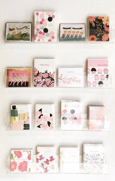 Colorful greeting cards arranged in a grid on a white wall.