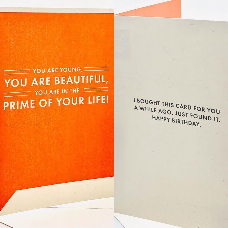 Birthday card open to an orange left page and cream right page with bold uplifting text.