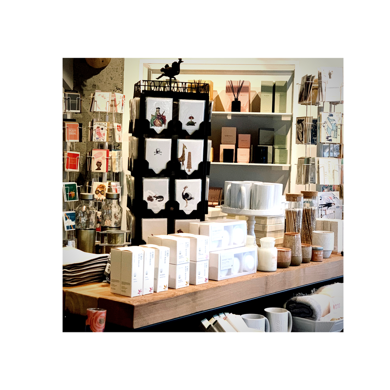 Shelves of stationery and gift items in a boutique shop, with neatly arranged boxed products on a wooden table