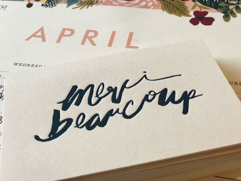 Stack of wedding invitations with “Mary Beach” in dark script on a cream card over an April calendar page