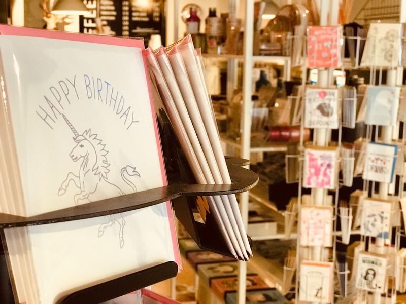 Greeting cards displayed in a shop, including a pink 