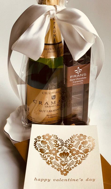 Valentine’s gift basket with champagne, chocolates, and a “happy valentine’s day” card.