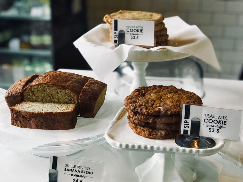 Bakery display of assorted pastries and cookies on white stands with price tags
