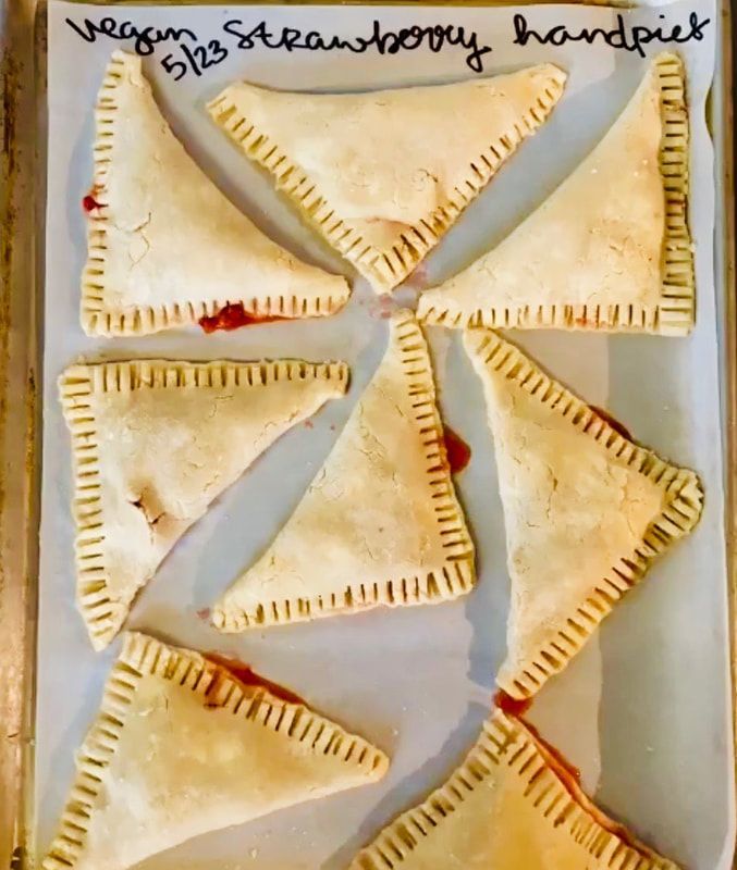 Assorted triangular pastries on a tray, brushed golden brown with visible filling near the edges