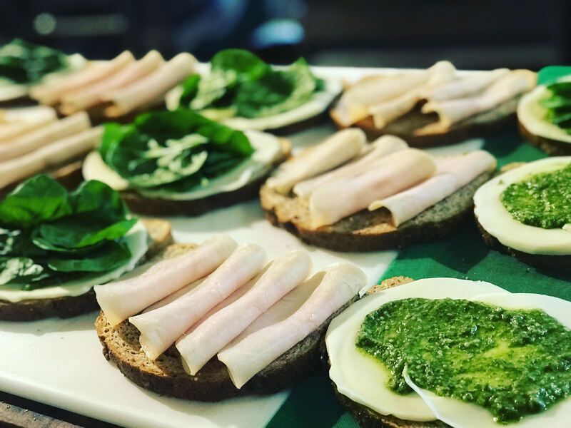 Open-faced sandwiches with green spread and white topping arranged on a tray