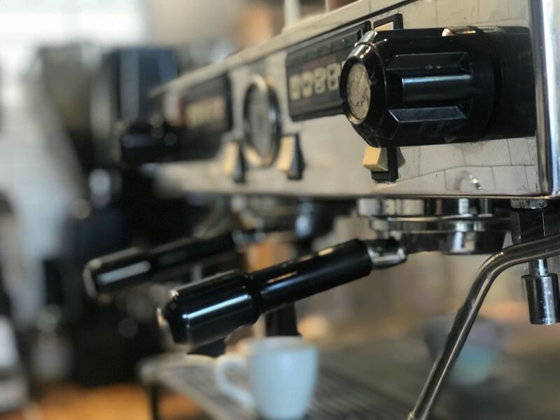 Close-up of an espresso machine with portafilter and a white cup underneath