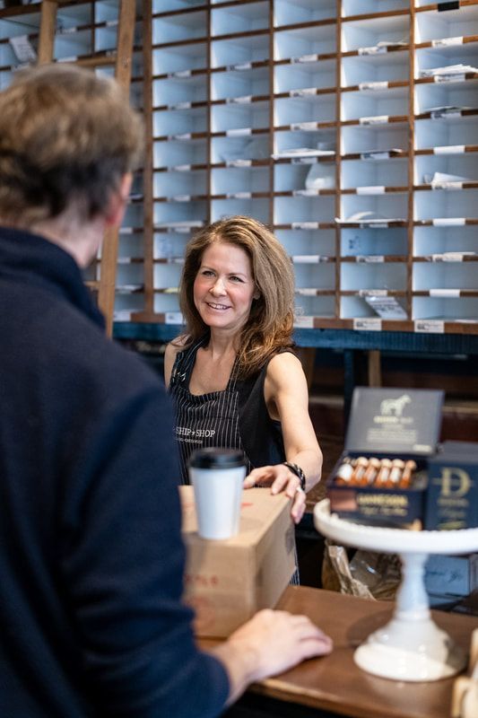 Woman behind a counter handing a coffee cup to a customer in a café