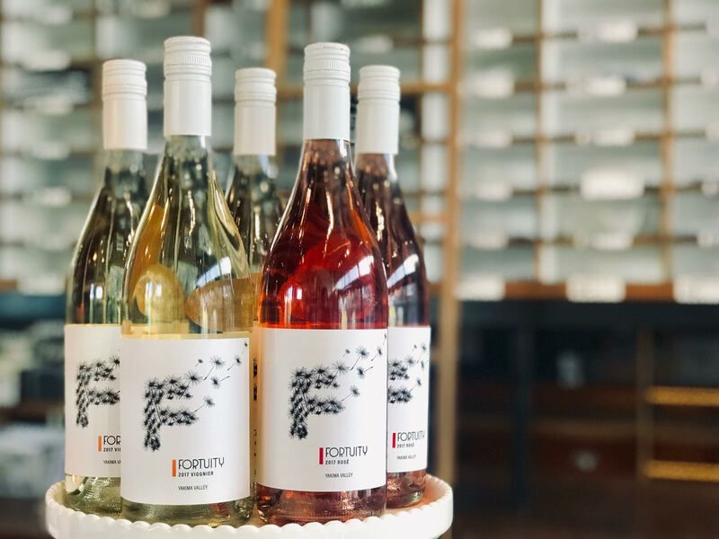 Assorted wine bottles on a table in a tasting room, with white, rosé, and red wines