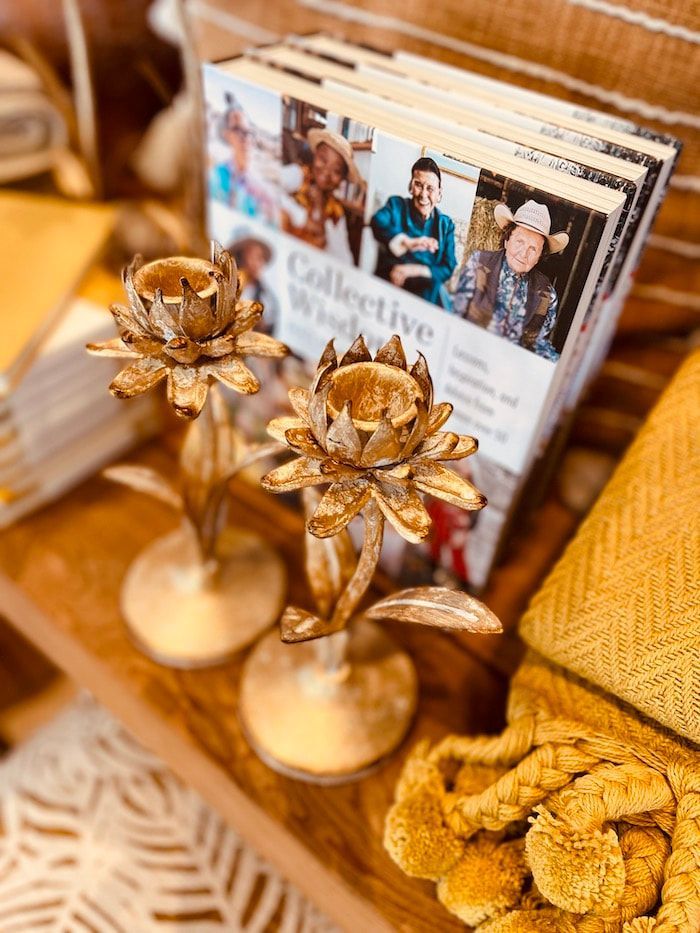 Gold flower candle holders on a table with magazines and a yellow woven basket