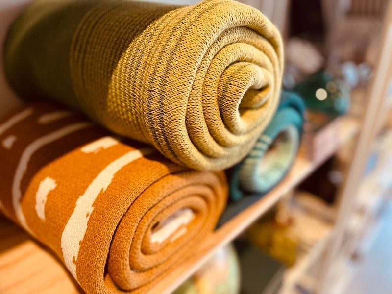 Rolled yellow and orange woven blankets stacked on a shelf
