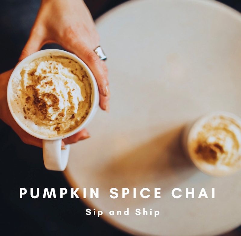 Hand holding a frothy pumpkin spice chai cup beside another cup on a table, with text overlay.