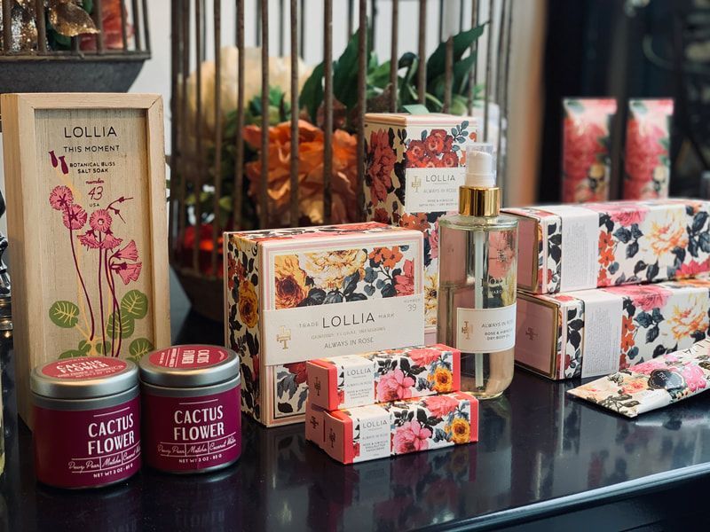 Lollia floral bath and body gift set with soaps, lotion, and perfume arranged on a shelf