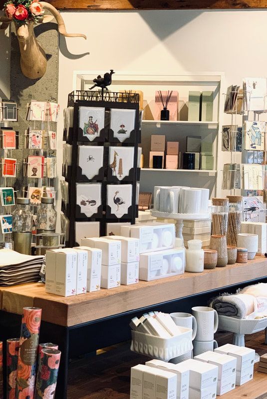 Gift shop display with candles, boxes, cards, and small home decor items on wooden shelves
