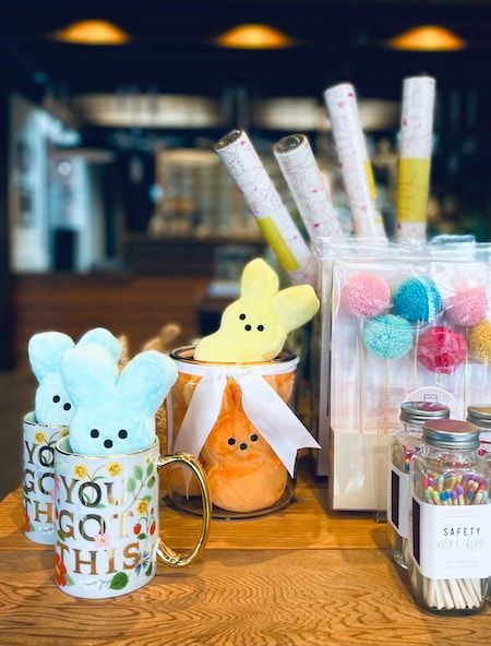 Cute pastel plush bunnies and candy in a jar on a wooden table at a cafe counter