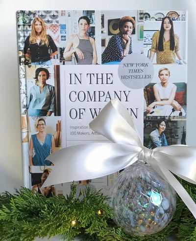 Book cover with a silver bow and holiday greenery, showing portraits around the title “In the Company of Women.”