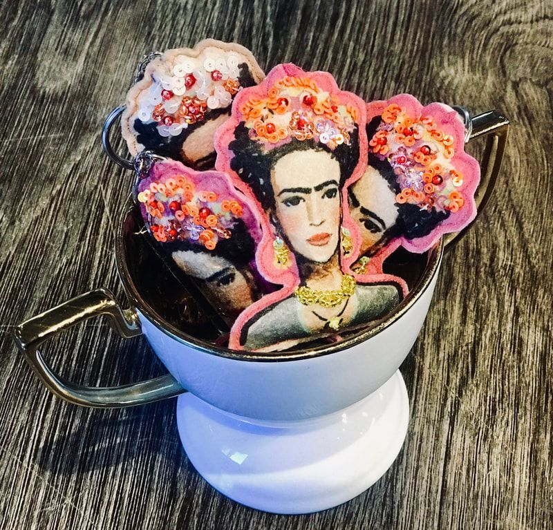 Decorated mug topped with colorful Frida Kahlo-style cookies on a wooden table