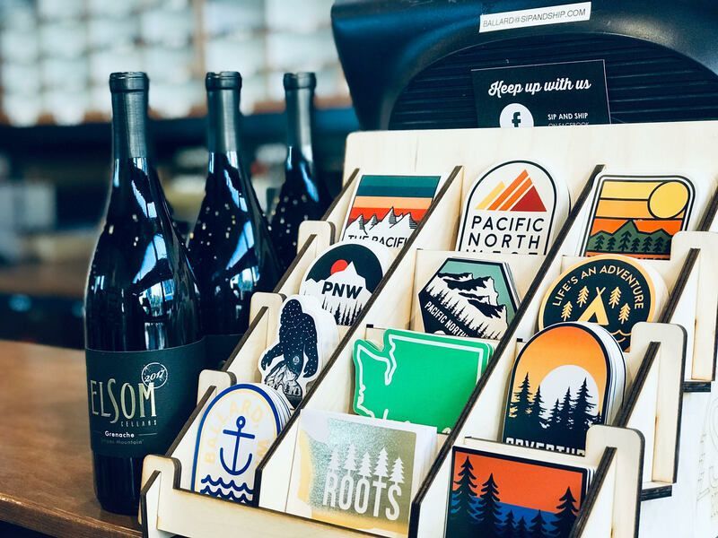 Assorted wine bottles and colorful Oregon-themed sticker designs displayed on a table