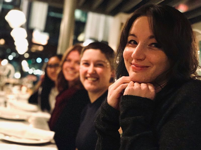 Three people smiling at a candlelit dinner table in a cozy restaurant