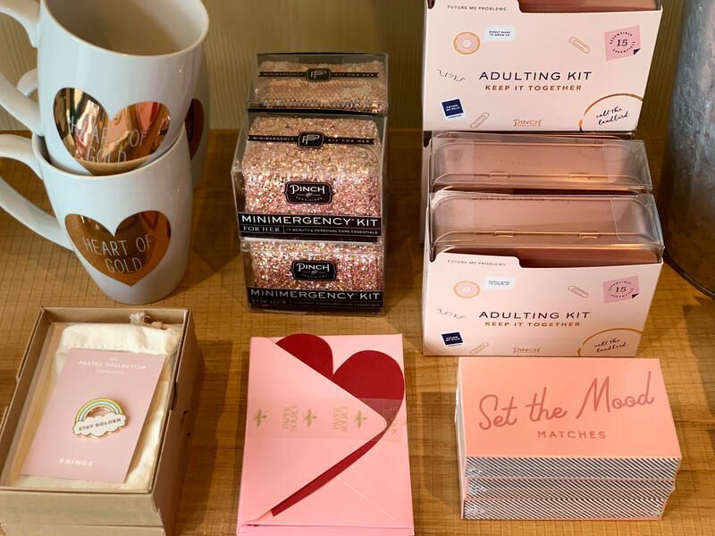 Assorted pastel gift boxes and mugs arranged on a wooden surface.