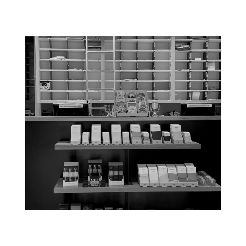 Black-and-white display shelves stocked with boxed products and bottles in a store aisle