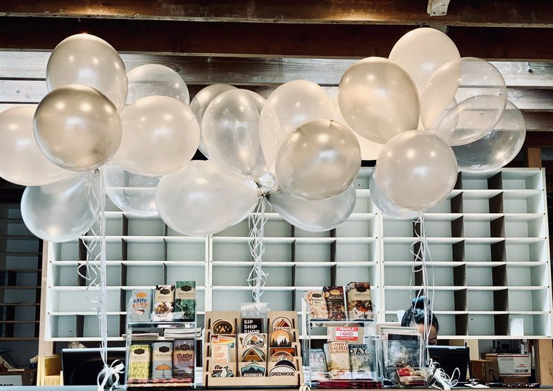 Balloon-decorated dessert display with pastries and menu cards on a counter in a cafe