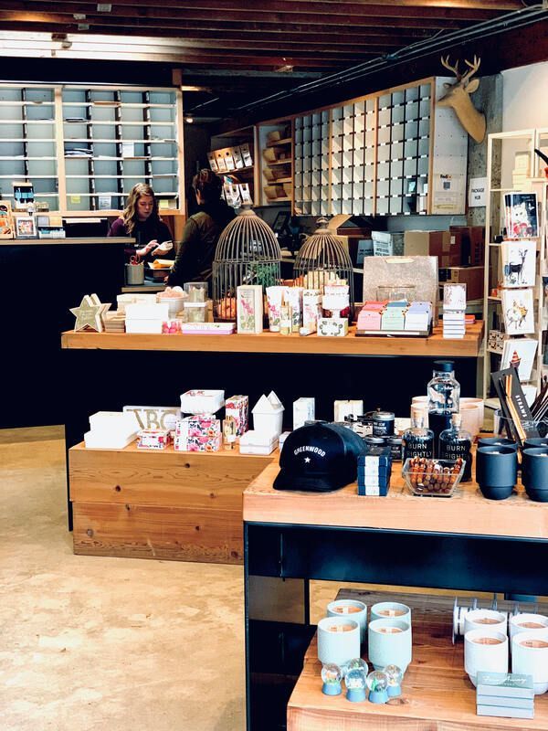 Cozy café with shelves of packaged goods, a counter, and a barista behind the register.