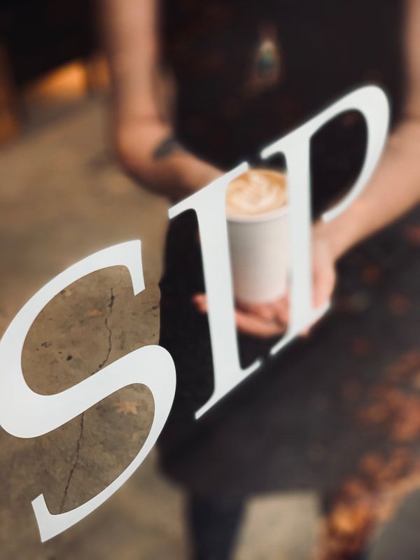 White “SIP” lettering over a blurred person holding a coffee cup in a dim setting