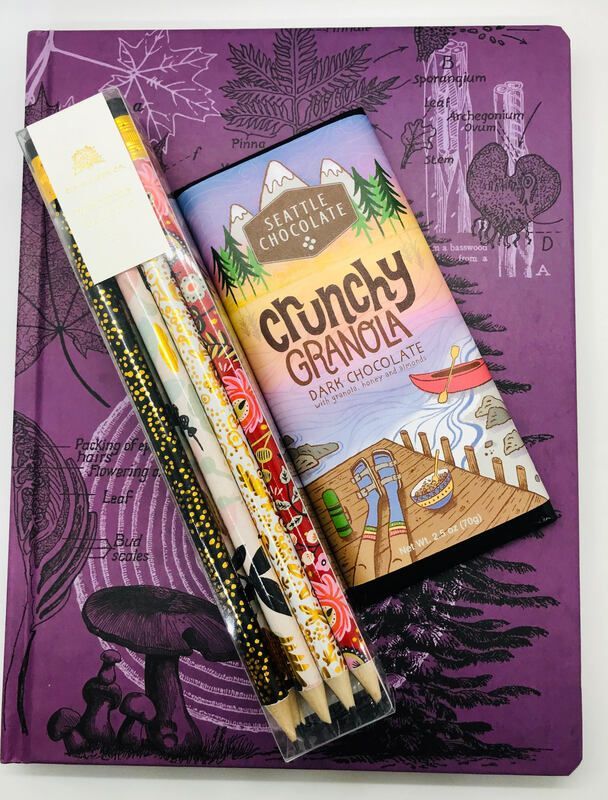 Purple notebook with a packaged crunchy granola bar and pencils on top