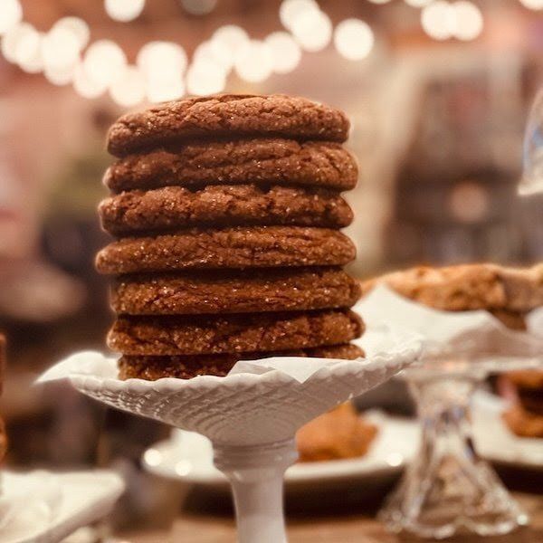 Stack of cinnamon sugar donuts on a white pedestal stand at a warmly lit bakery display