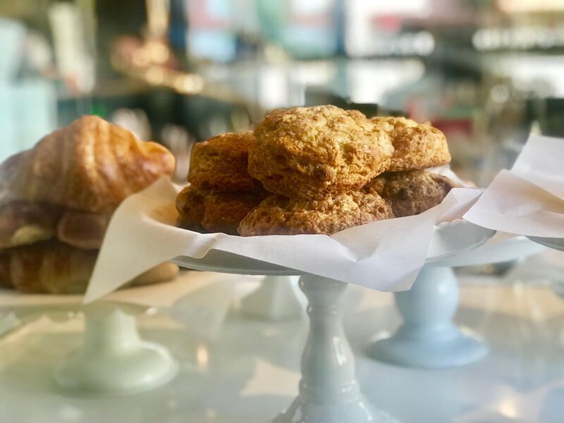 Pastries on white cake stands in a bakery display, including a croissant and crumb cake.