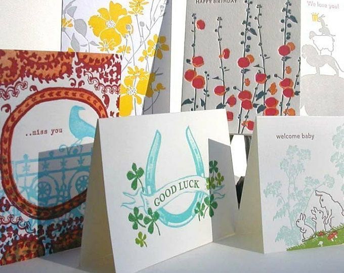 Assorted colorful greeting cards with floral and baby-themed designs on a display stand