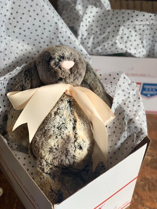 Plush gray rabbit in a gift box with tissue paper and a cream ribbon bow