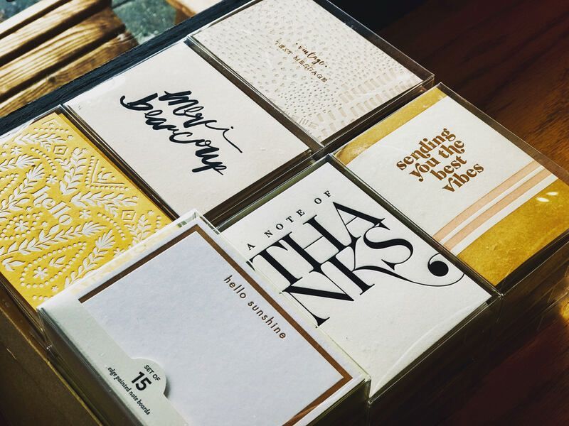 Neatly arranged square book covers on a wooden surface, mostly white with gold and black typography.