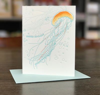 Jellyfish-themed birthday card with pastel blue and orange artwork on a tabletop