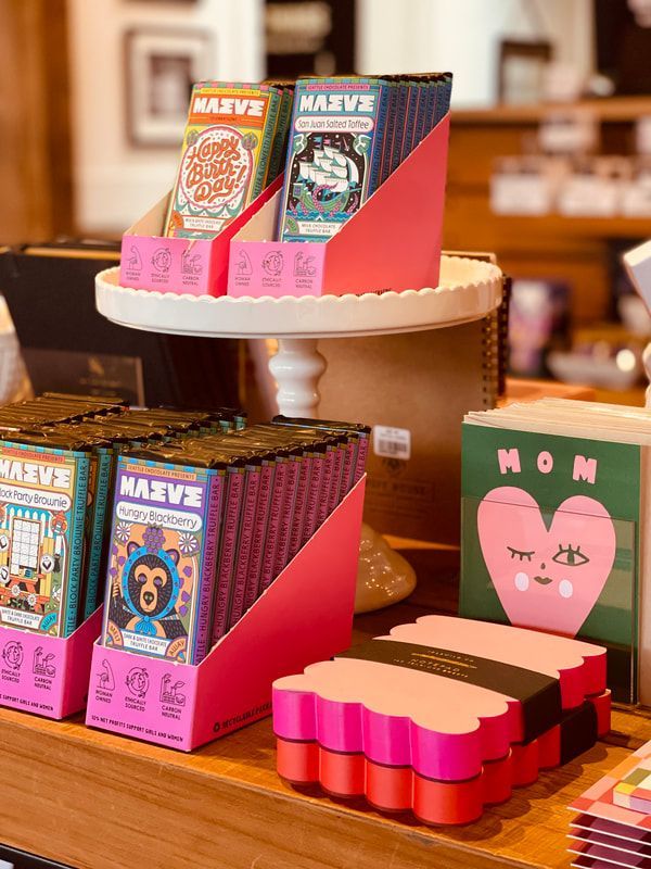 Colorful gift boxes and small packaged items displayed on a tiered wooden table in a shop.