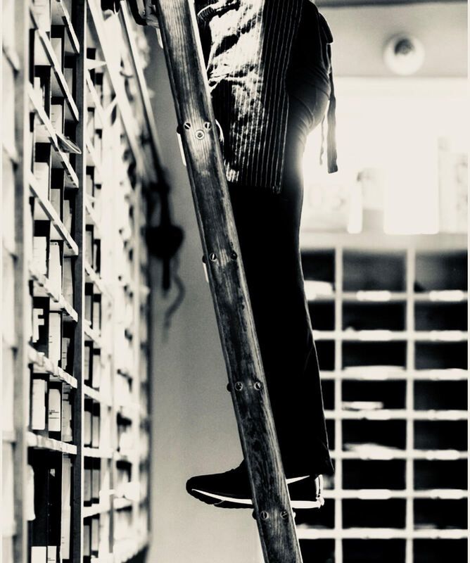 Person climbing a ladder in a bright room with mail cubbies and shelves