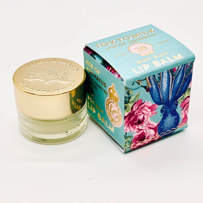 Gold-lidded lip balm jar beside turquoise floral box packaging