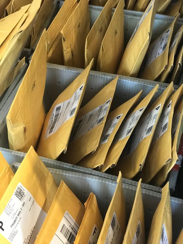 Rows of yellow padded envelopes stacked in metal mail sorting bins