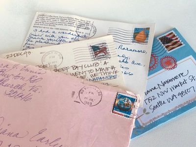 Assorted handwritten envelopes and postcards with stamps and postmarks scattered on a light surface